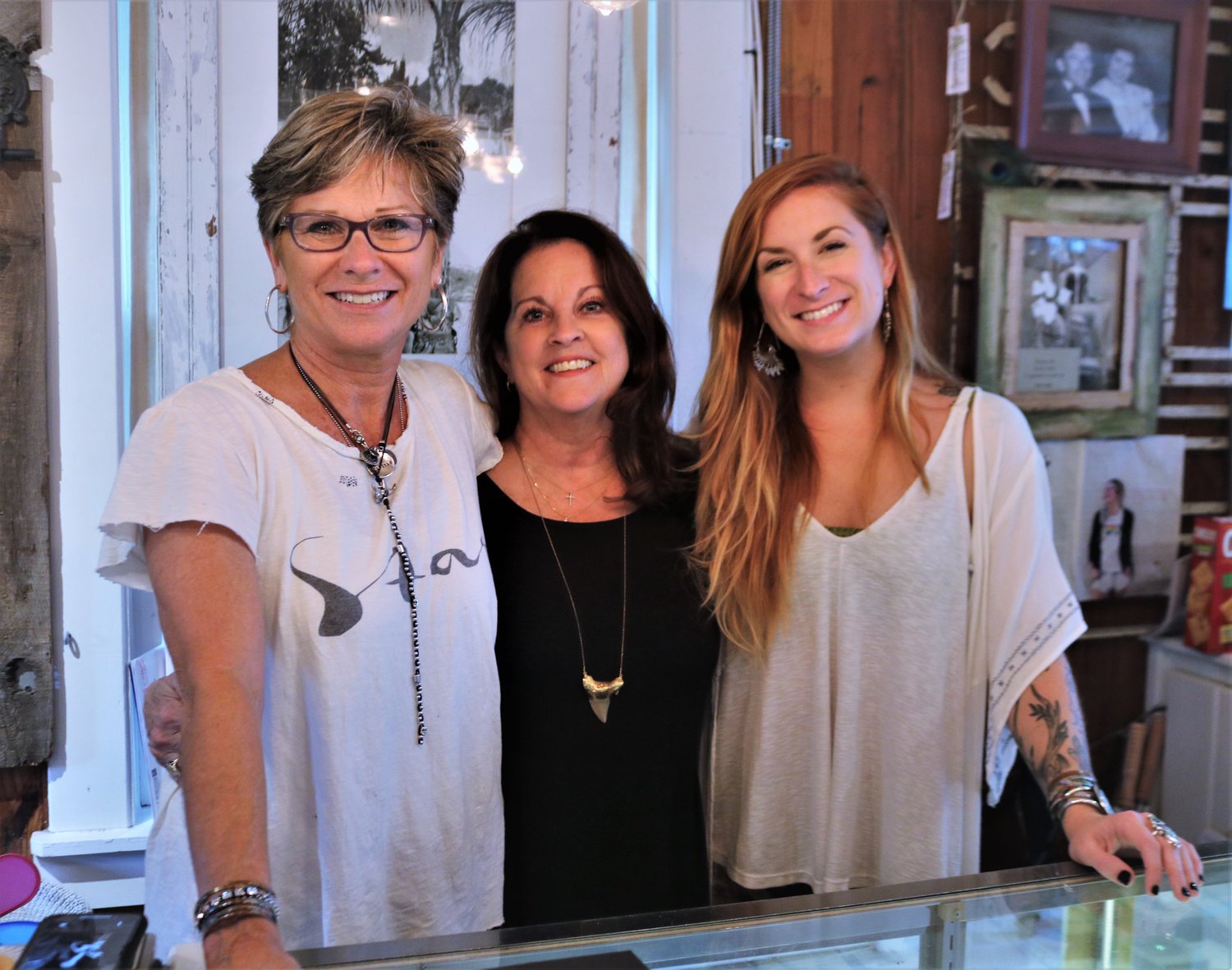 Left to Right) Cathy Thomasson, Jodi Burns and Cara English pose in front of the photo of Sidney Cardel, Thomasson’s mother and inspiration behind the Sidney Cardel boutique.